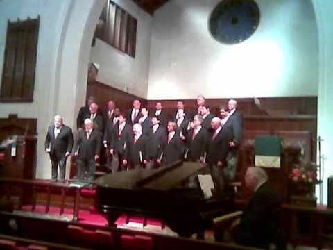 a group of men in suits and ties standing on a stage next to a piano