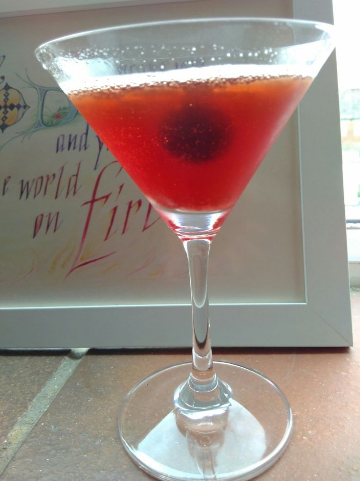 a glass filled with liquid sitting on top of a table next to a framed photo