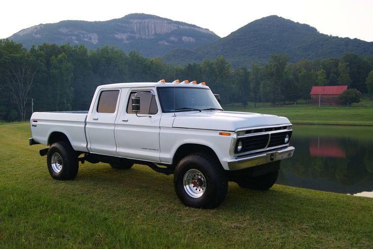 a white pick up truck parked next to a lake