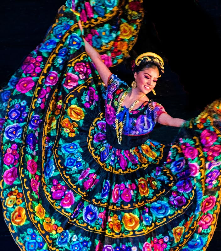 a woman is dancing with colorful cloths around her