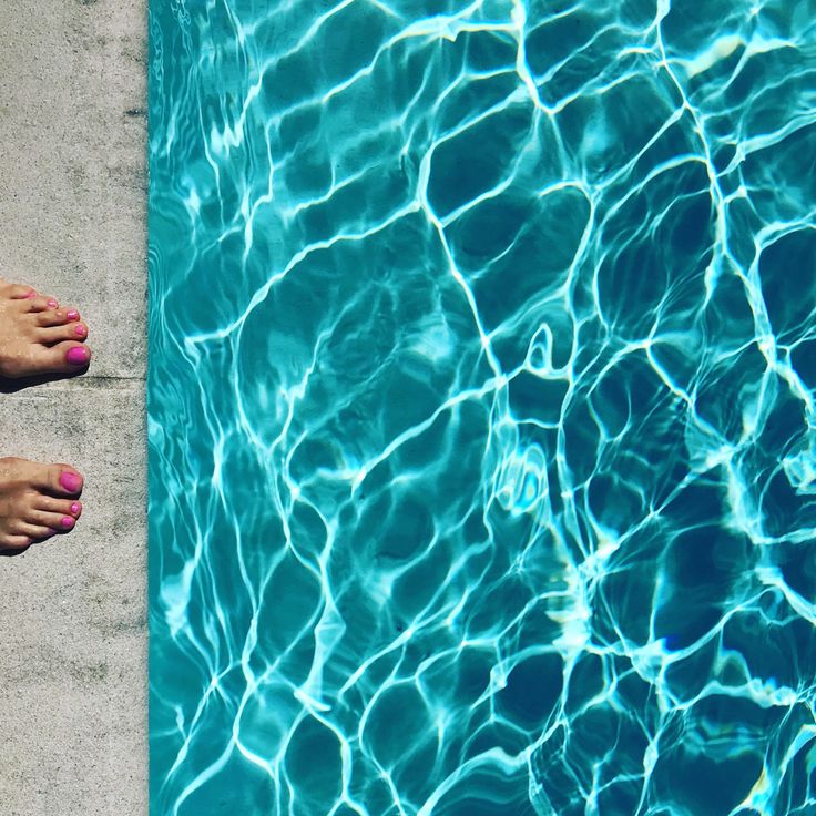 two pairs of flip flops sitting on the edge of a swimming pool next to each other