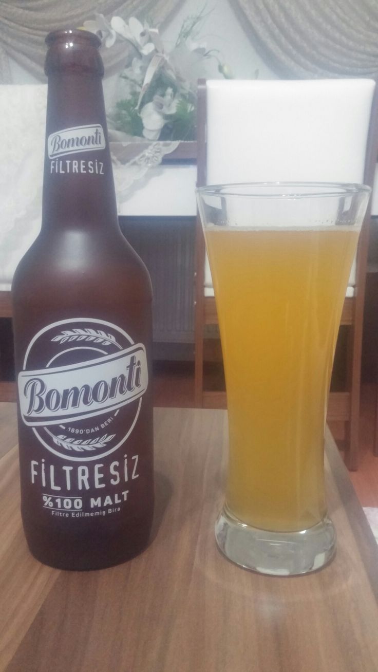 a bottle and glass sitting on top of a wooden table