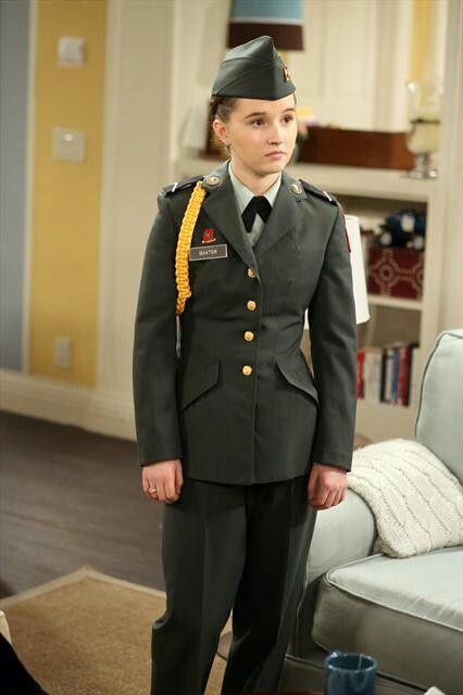 a woman in uniform standing next to a couch