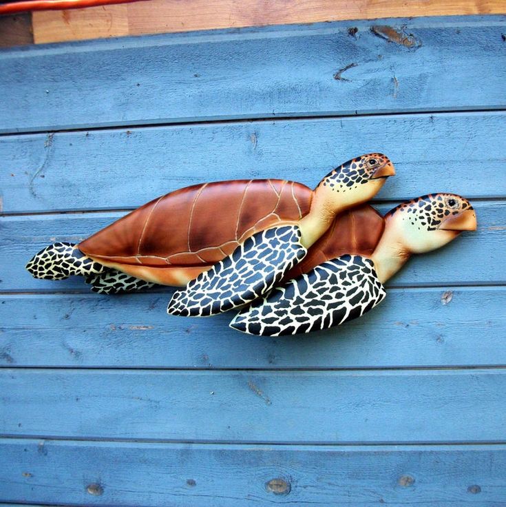 a statue of a turtle on the side of a blue wooden wall with it's head resting on its back