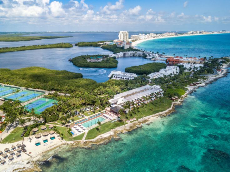 an aerial view of the resort and tennis courts in front of the ocean, surrounded by palm trees