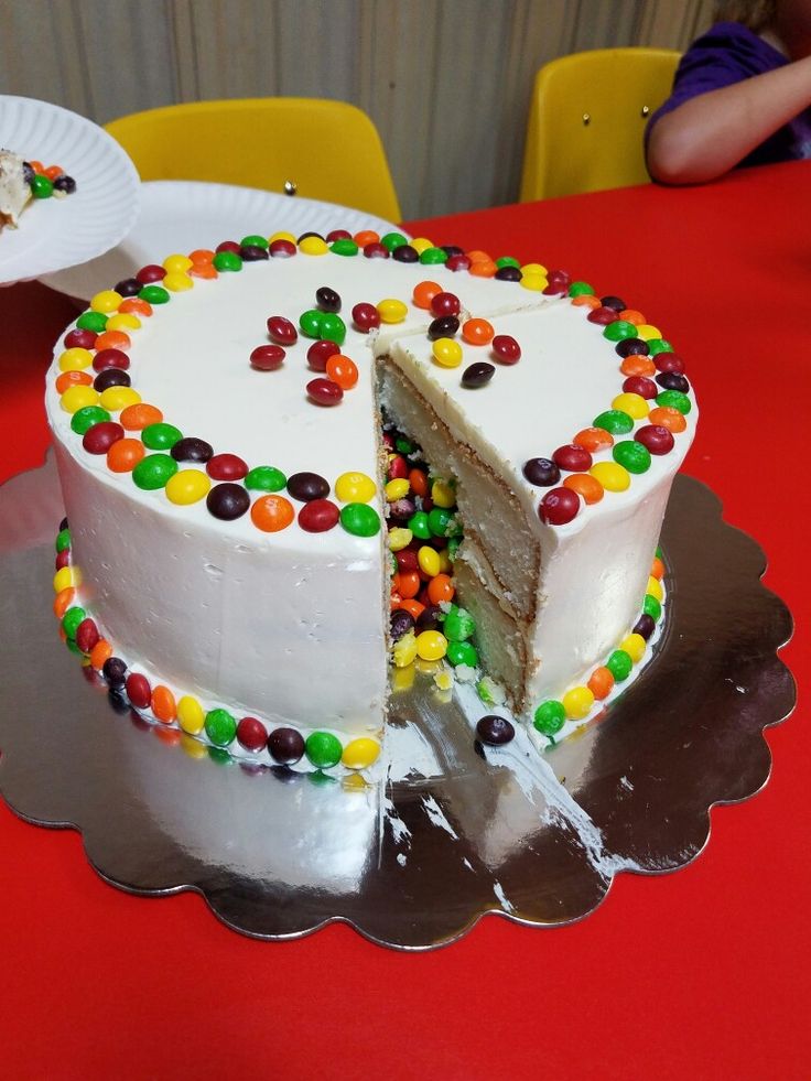 a large white cake with jelly beans on it's side is cut in half