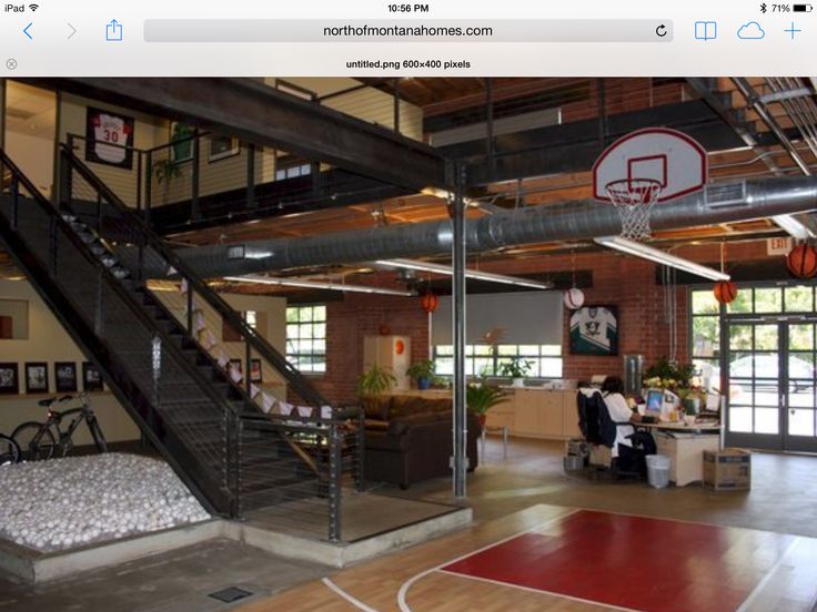 an indoor basketball court with stairs leading up to the second floor and people sitting at tables