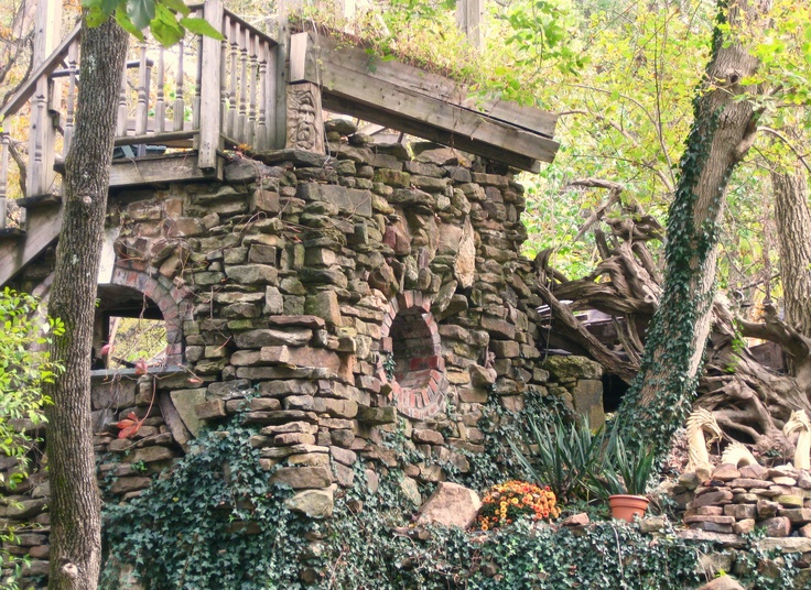 an old stone building surrounded by trees and plants