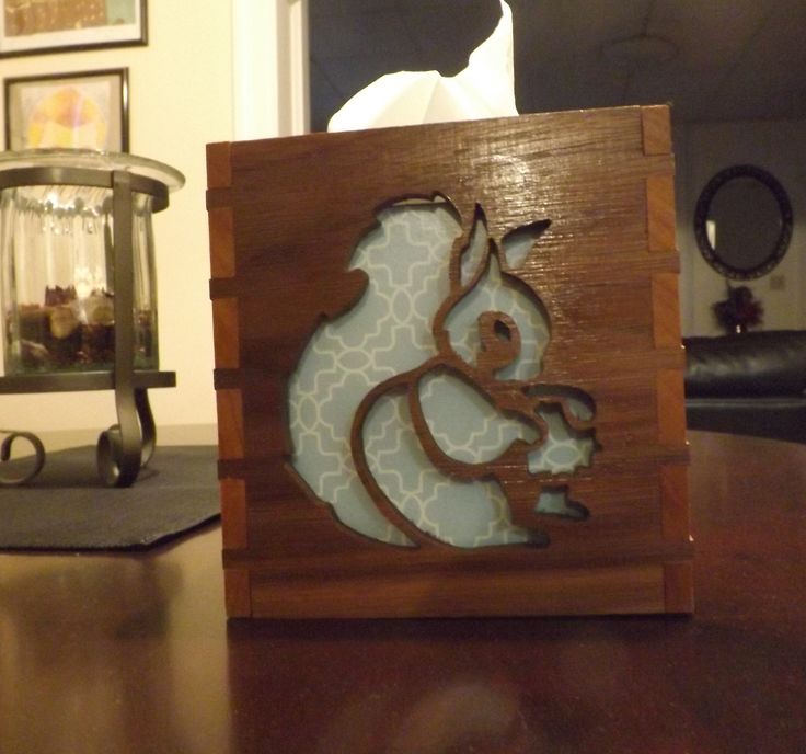 an animal cut out on top of a wooden box sitting on a table next to a candle holder