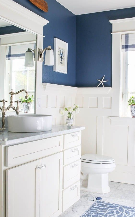 a bathroom with blue walls and white cabinets