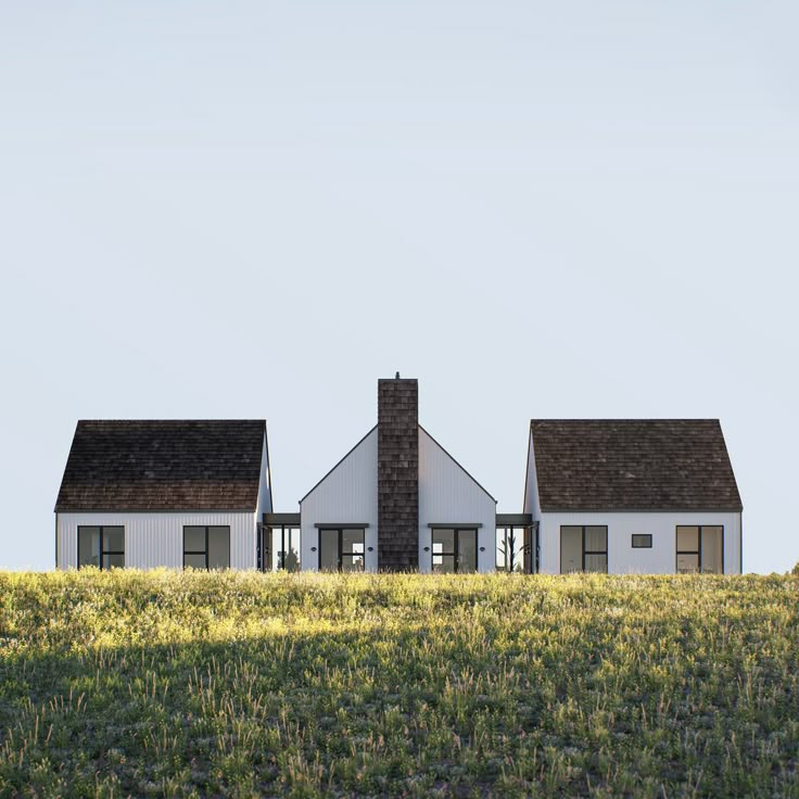 two white houses sitting on top of a lush green field