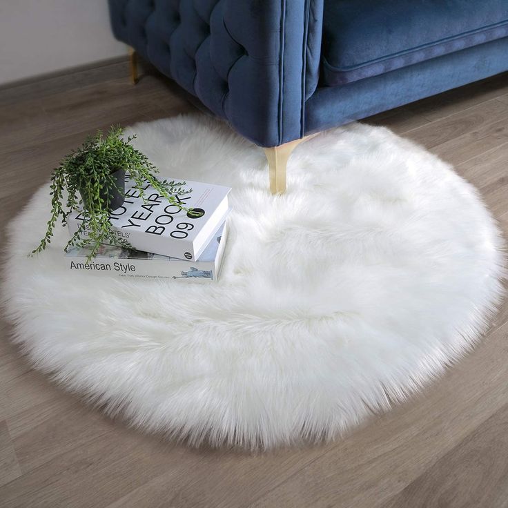 a round white rug sitting on top of a wooden floor next to a blue couch