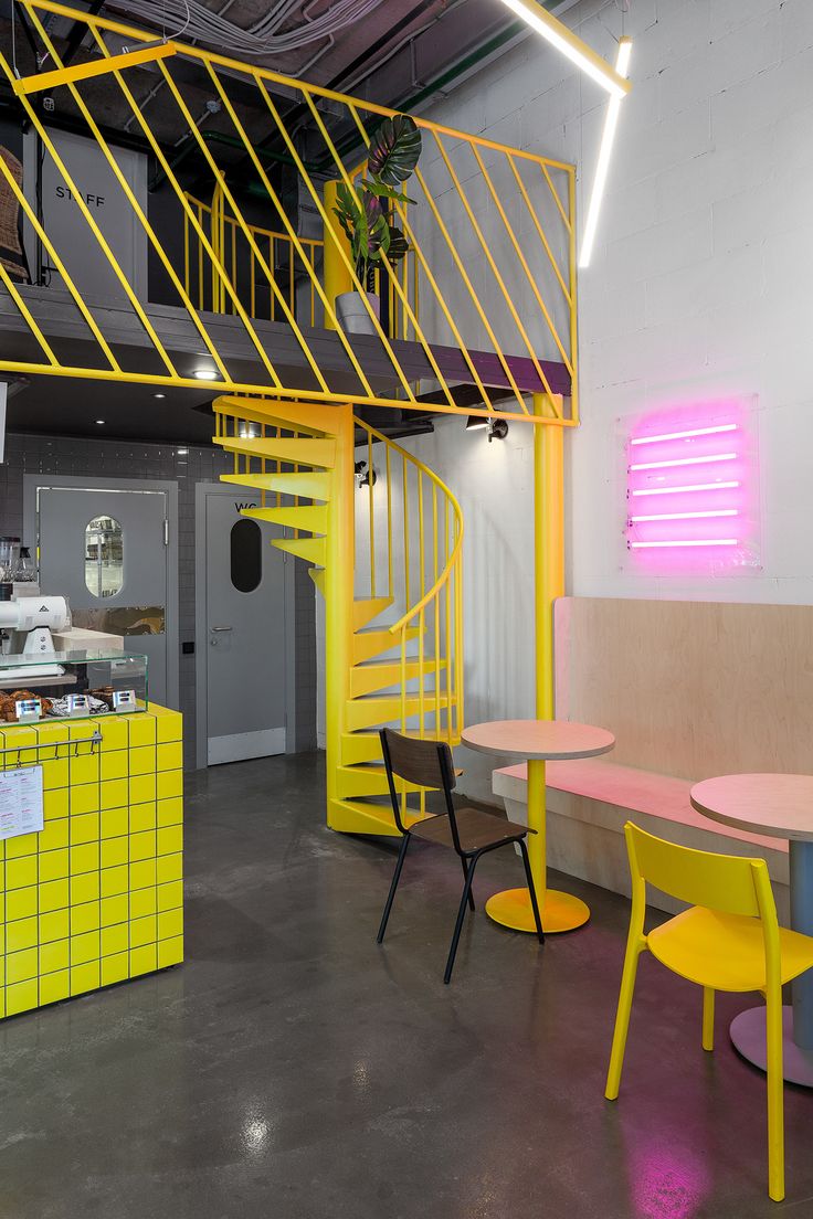 the interior of a restaurant with yellow and pink tables