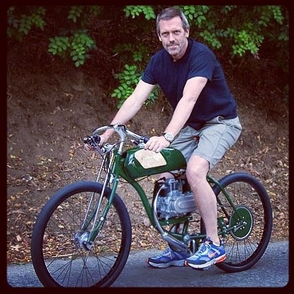 a man riding on the back of a green motorbike in front of trees