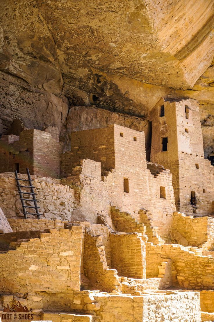 the cliff houses are built into the side of the mountain, with people walking around them