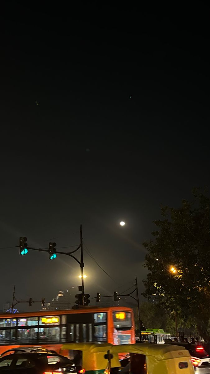 a city street filled with lots of traffic under a green traffic light at night time