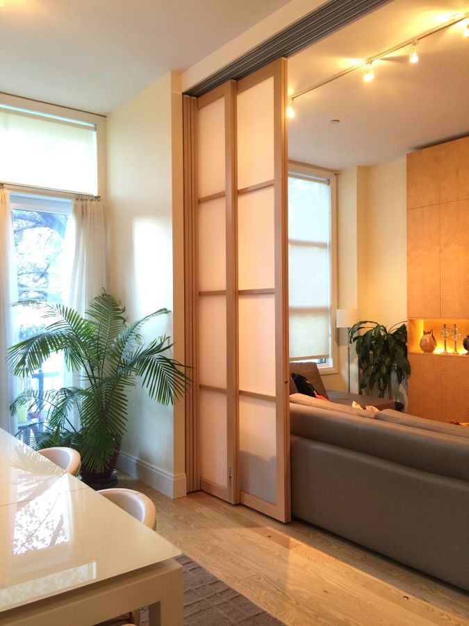 a living room filled with furniture next to a window and a plant on top of a hard wood floor