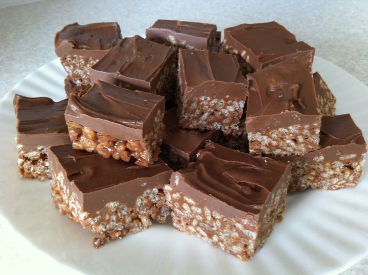 a white plate topped with lots of chocolate and granola bar pieces on top of each other