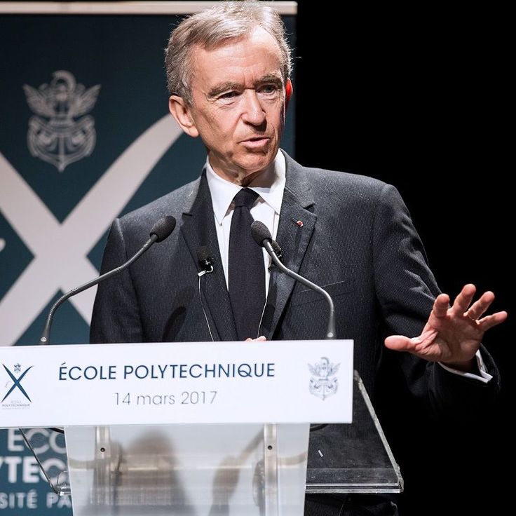 a man in a suit and tie standing at a podium with his hands out to the side