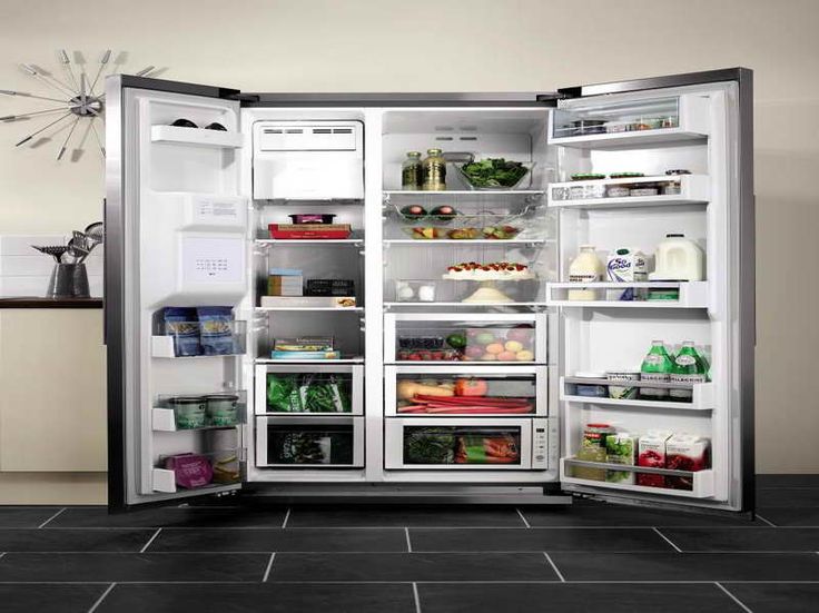 an open refrigerator with its door wide open and full of food items inside, sitting on a tiled floor