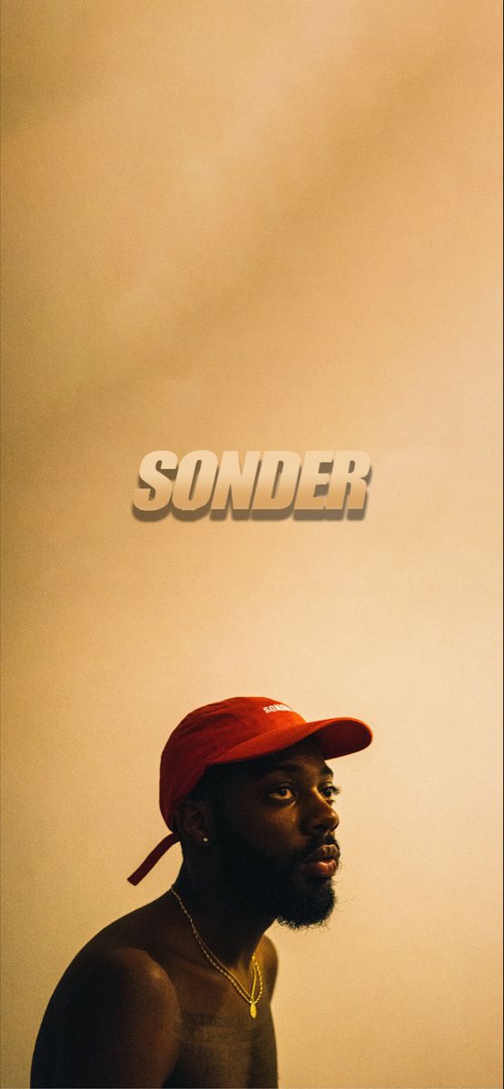 a man wearing a red hat standing in front of a wall with the word sounder on it