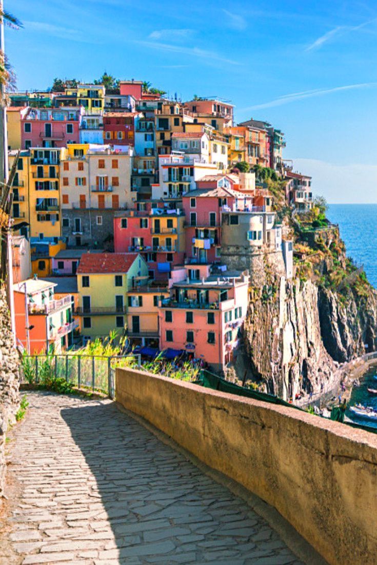 the colorful buildings are on top of the cliff by the water and blue sky with clouds