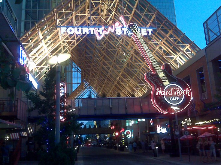 a city street at night with neon signs and lights on the building's roof