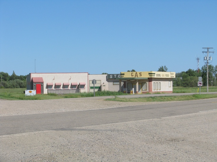 an empty road in front of a building with a sign on it that says gas station