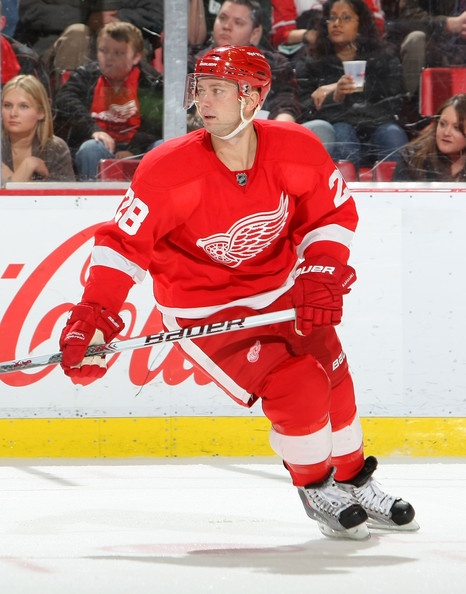 an image of a man playing hockey on the ice in front of people watching him