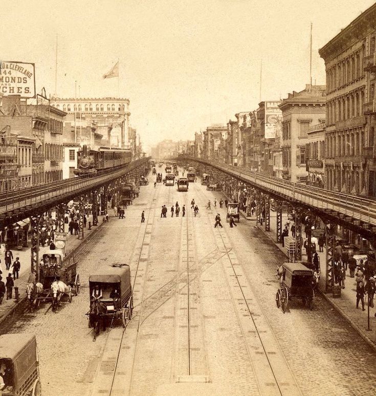 an old black and white photo of people walking on the street in front of train tracks