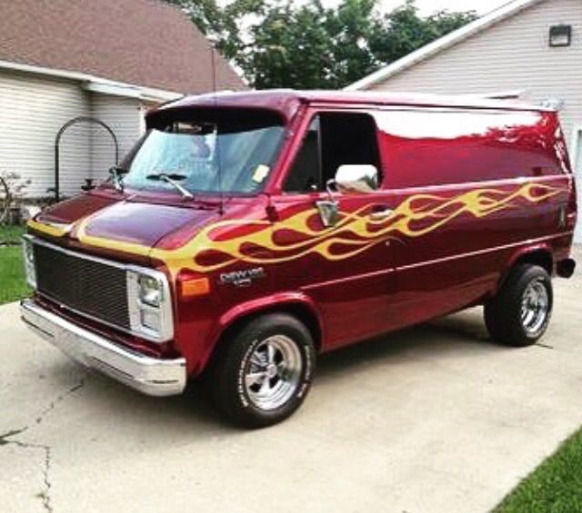 a red van with flames painted on the side parked in front of a garage door