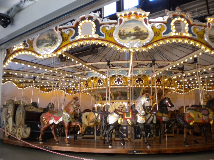 a merry go round with horses and people on it's sides in a building