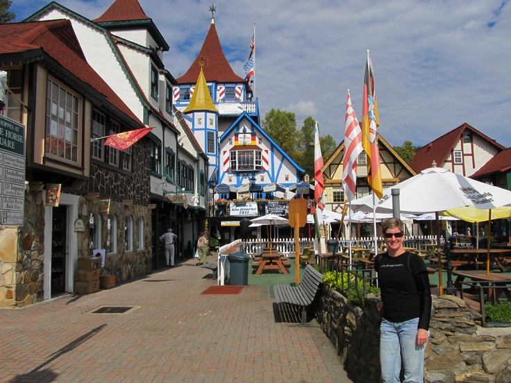 a woman standing in front of some buildings on a cobblestone road with flags