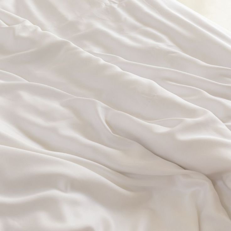 an unmade bed with white sheets and pillows