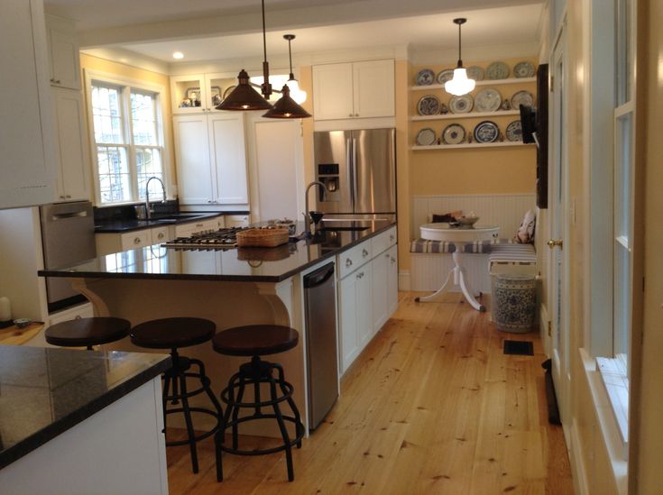 a kitchen with white cabinets and black counter tops next to an island in the middle