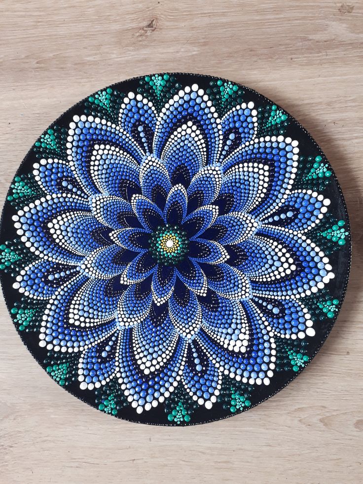 a blue and green flower painted on top of a wooden table