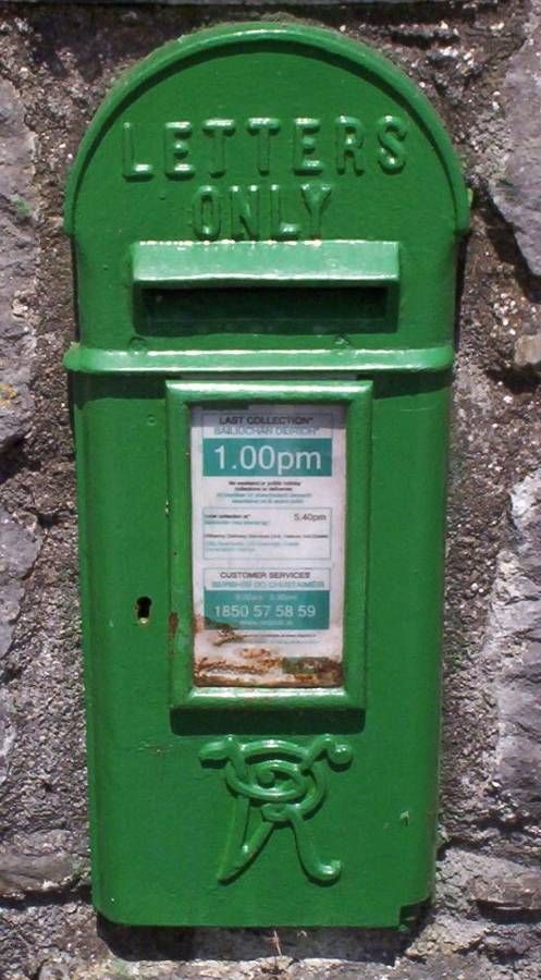 a green mailbox sitting on the side of a stone wall