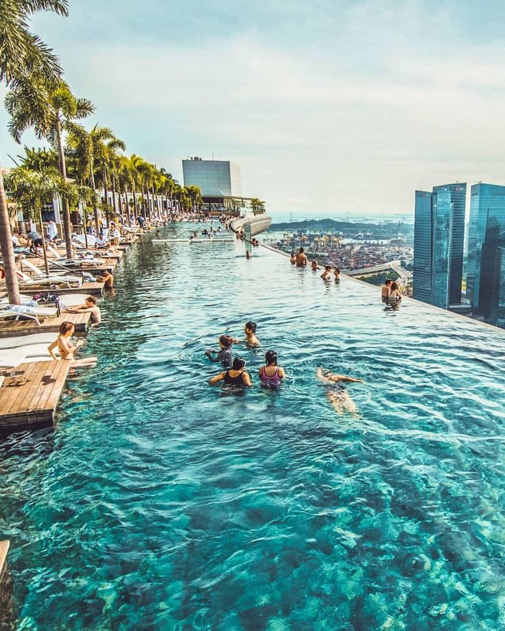 people are swimming in the water at an outdoor pool with skyscrapers in the background