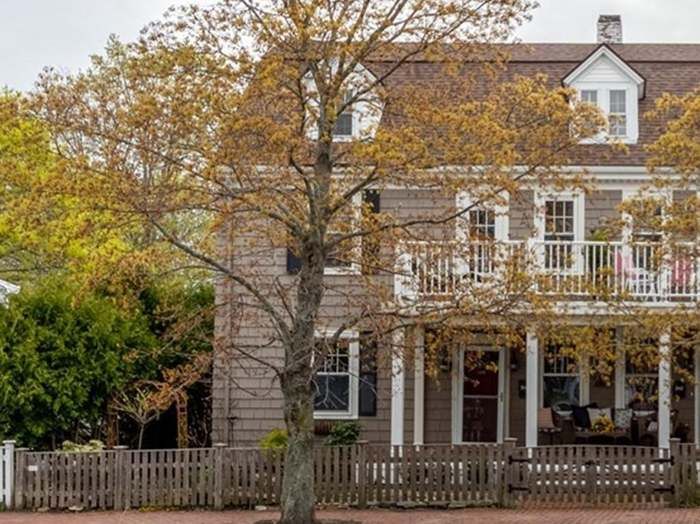 a large house sitting next to a tree with lots of leaves on it's branches