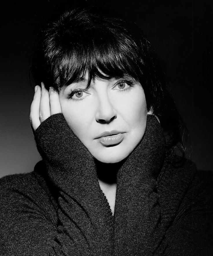 a black and white photo of a woman with her hand on her head looking at the camera