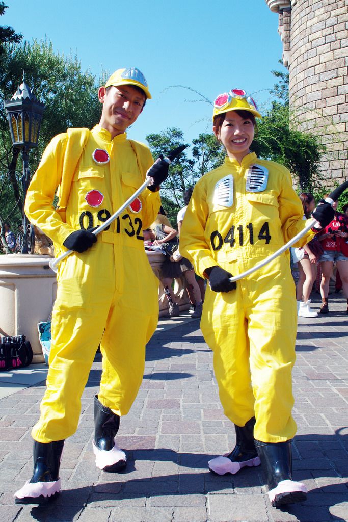 two people in yellow costumes are standing on the street with ski poles and holding sticks