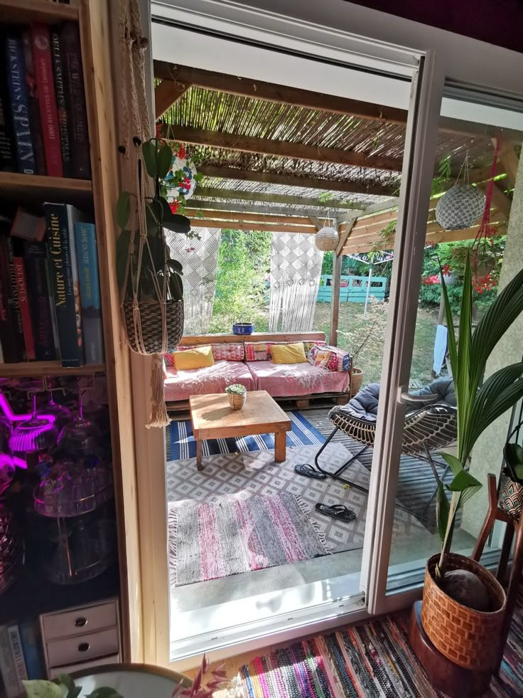 a living room filled with lots of furniture next to a patio covered in bookshelves