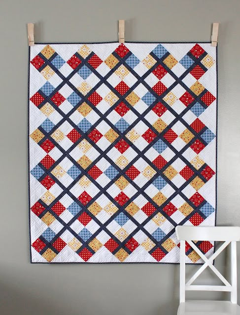 a quilt hanging on the wall next to a chair