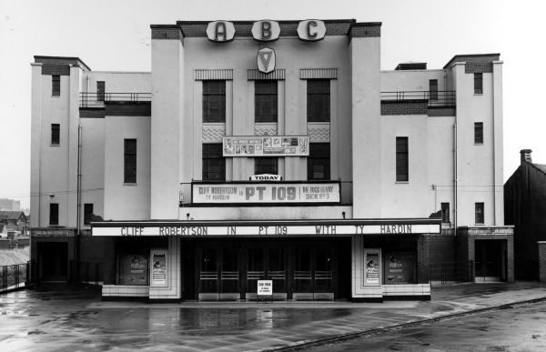 an old movie theater in the middle of town on a rainy day with no people