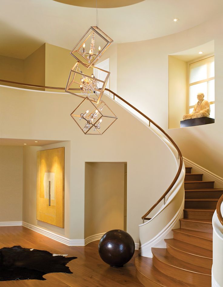 a spiral staircase with chandelier hanging from it's side in a home