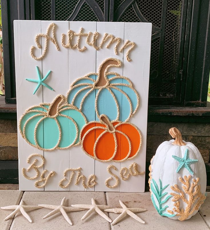 two pumpkins are sitting next to a sign that says autumn by the sea