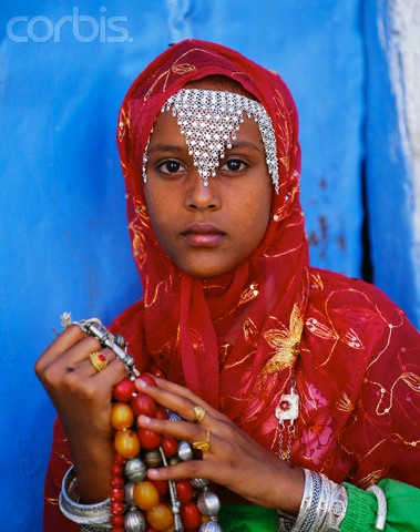 a young woman wearing a red headscarf holding beads