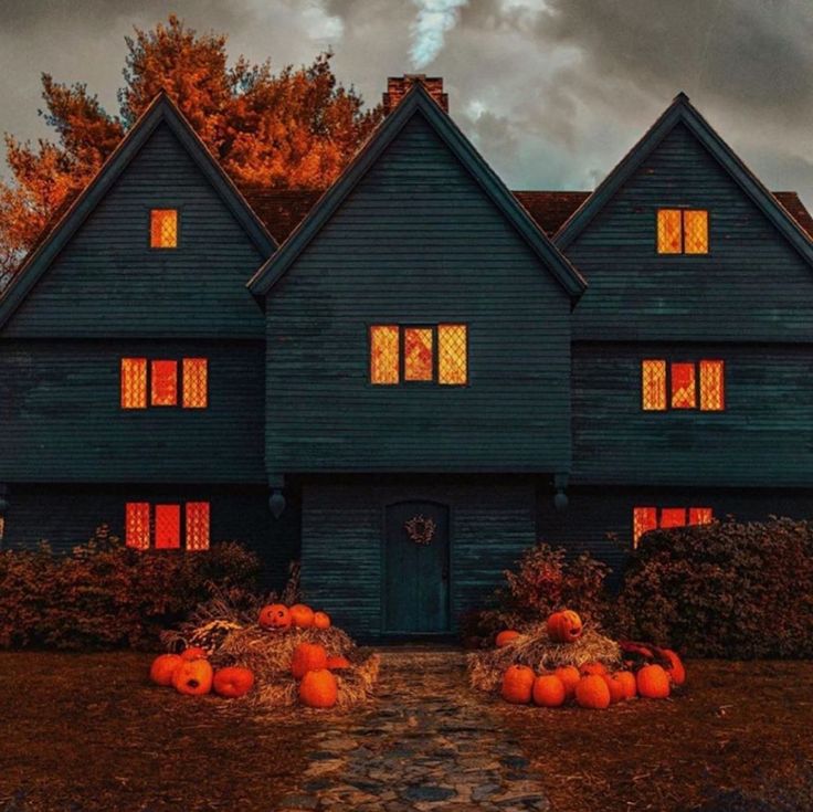 a house with pumpkins in front of it and the windows lit up at night