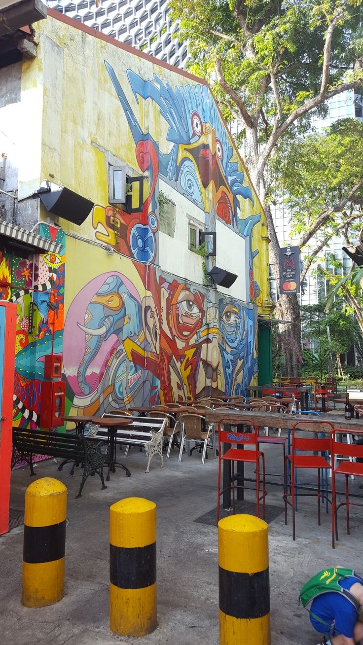 colorful mural on the side of a building with people sitting at tables and chairs around it