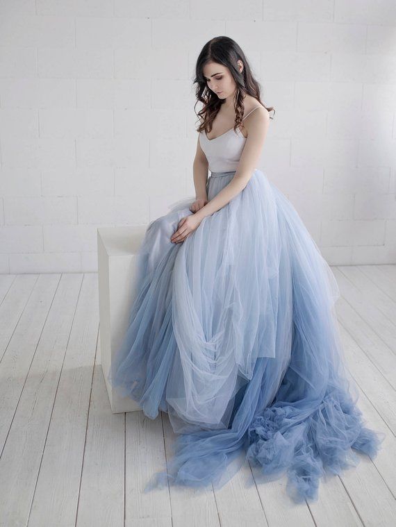 a woman in a blue dress sitting on a white bench